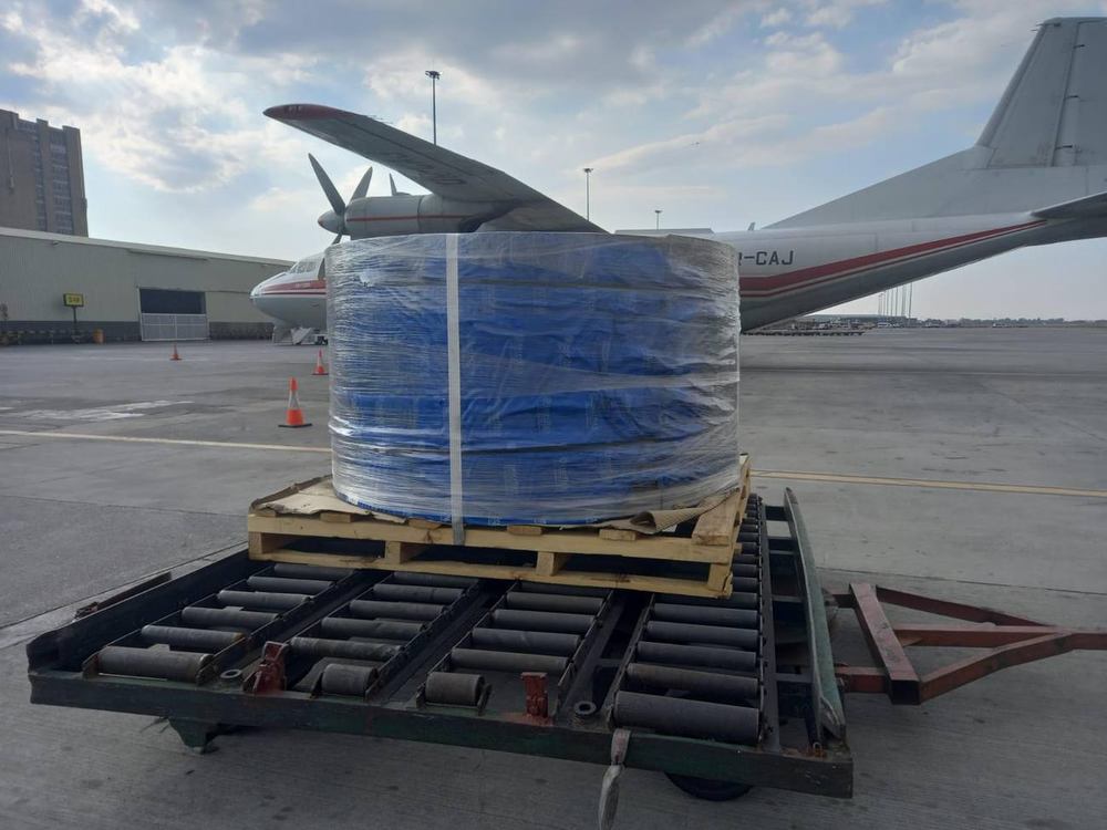 Outsize industrial cargo reel palletised beside an Antonov An-12 freighter on the cargo apron in Johannesburg