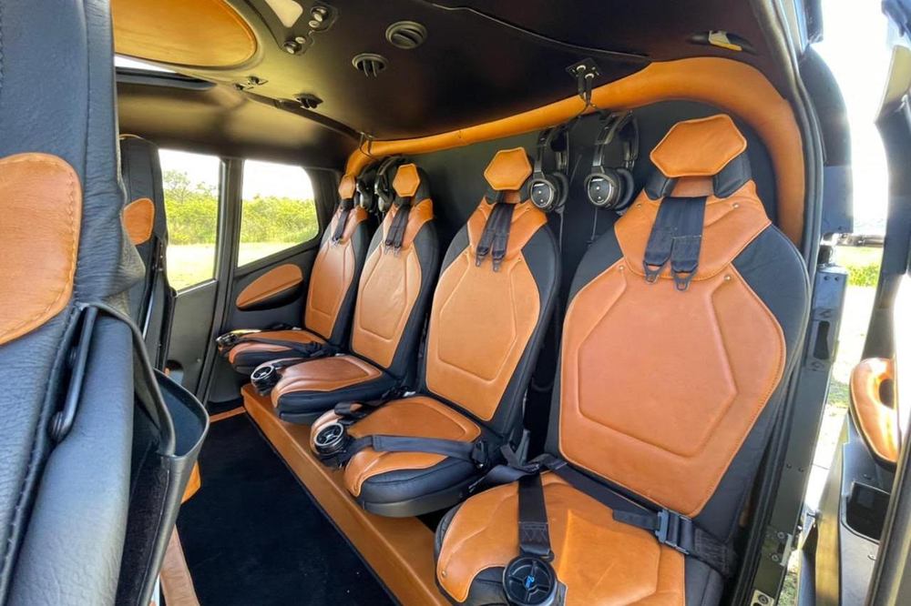 Tan leather helicopter cabin with noise-cancelling headsets fitted, prepared for a private transfer