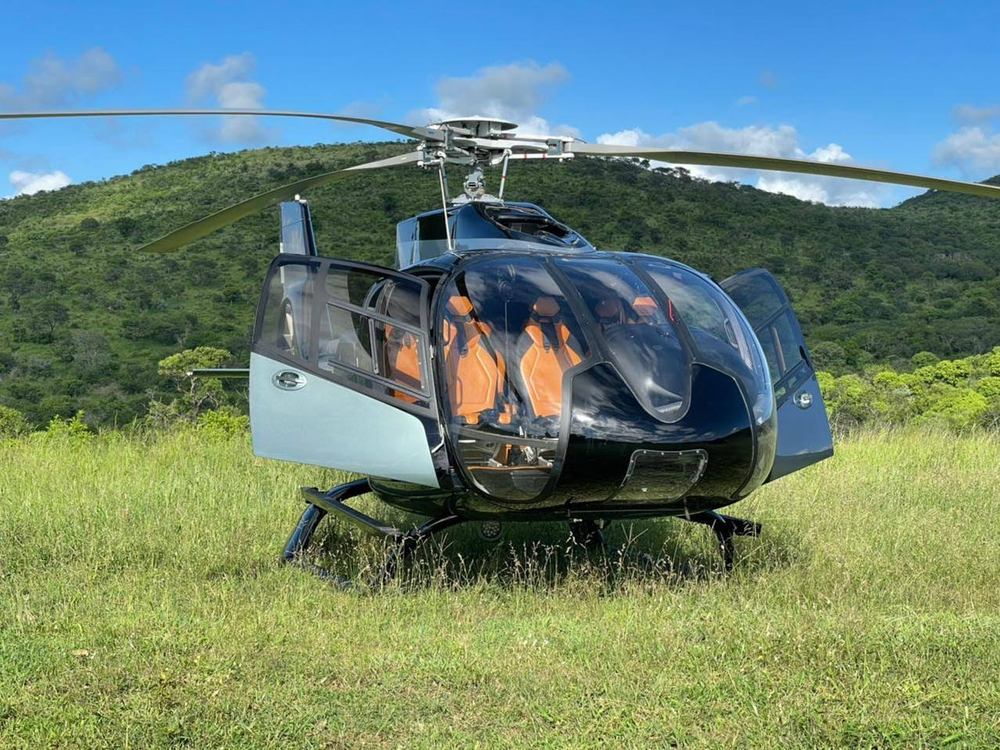 Airbus H130 helicopter with doors open on a grass hillside during a private leisure charter