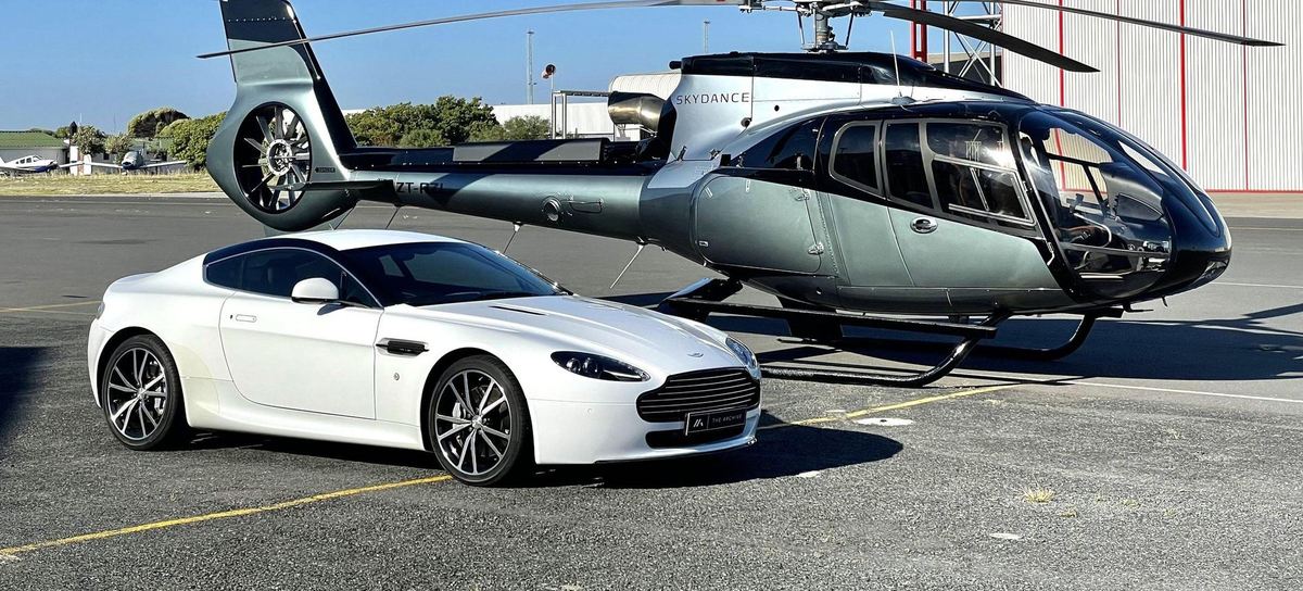 Charter helicopter on the apron beside a client vehicle, ready ahead of a scheduled pickup