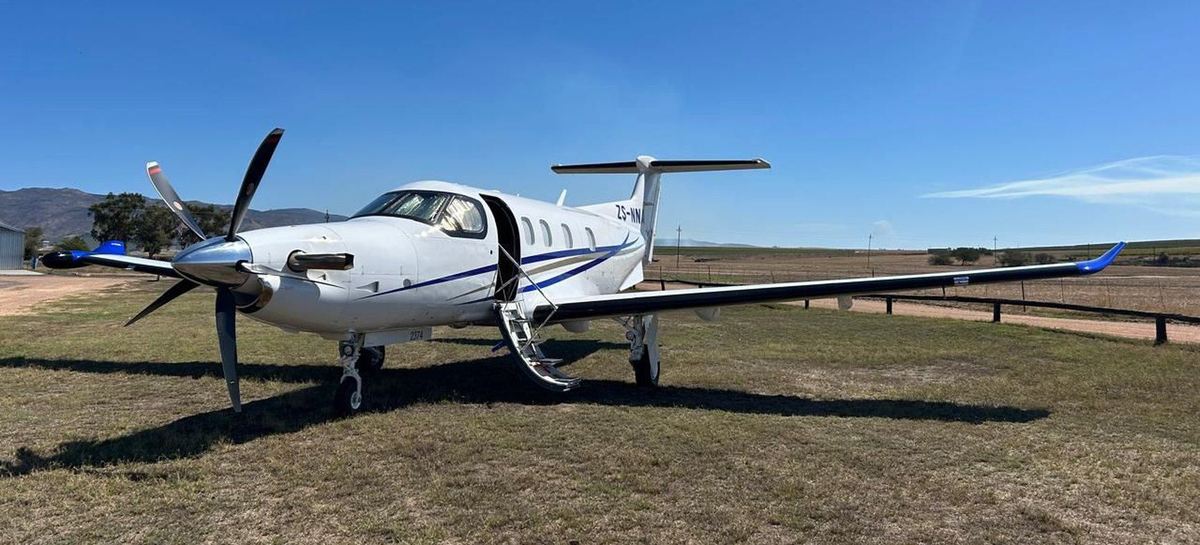 Pilatus PC-12 executive turboprop parked on a grass strip under clear sky