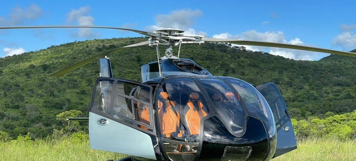Airbus H130 helicopter with doors open on a grass hillside during a private charter