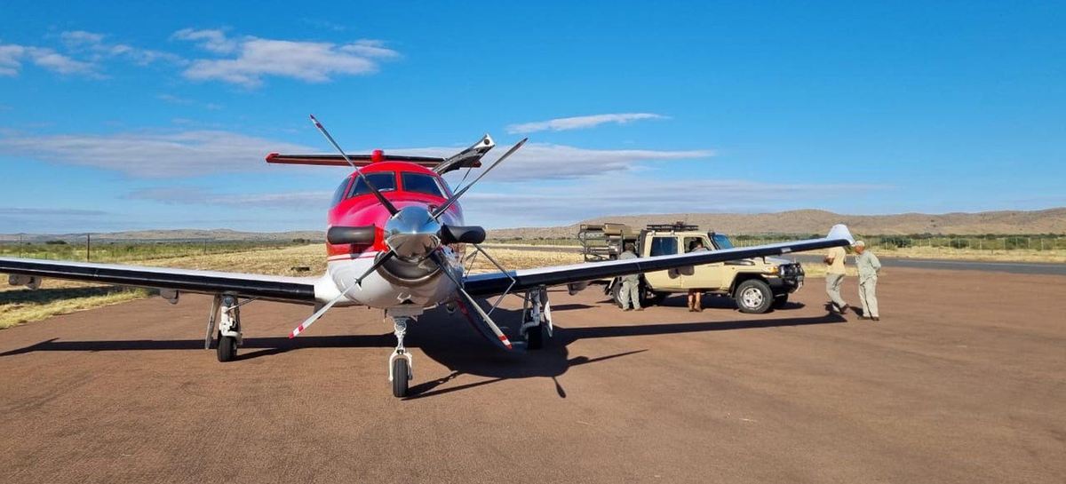 Pilatus PC-12 nose-on at a remote dirt strip with ground crew and support vehicle