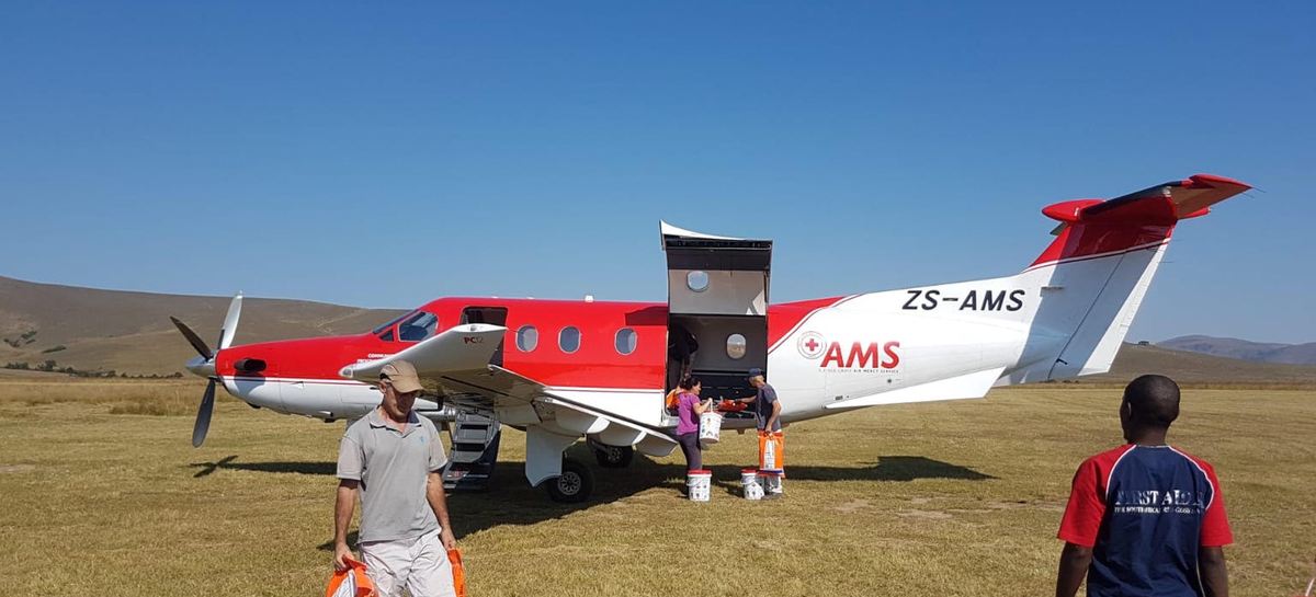 Pilatus PC-12 in air mercy service livery being unloaded by hand on a rural grass airstrip