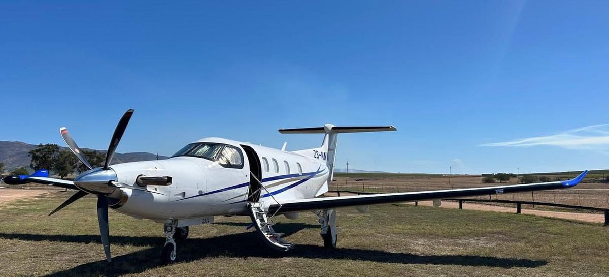 Pilatus PC-12 executive turboprop on a grass airstrip under clear sky before a charter departure
