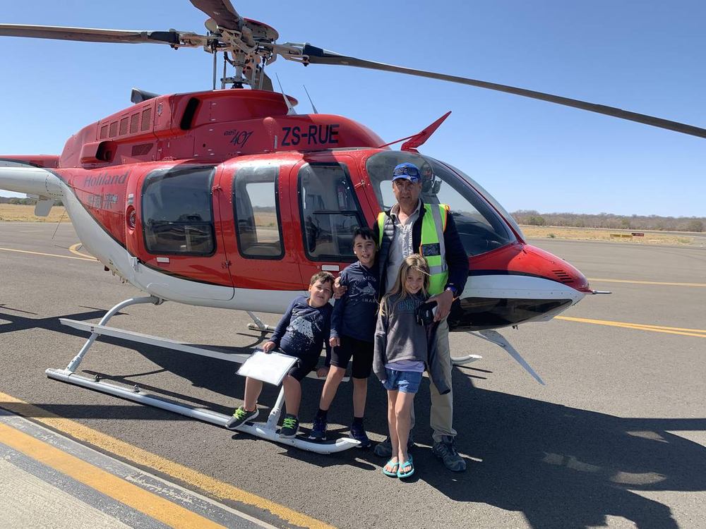 Aviation ONE pilot with young passengers beside a Bell 407 helicopter before a family charter flight