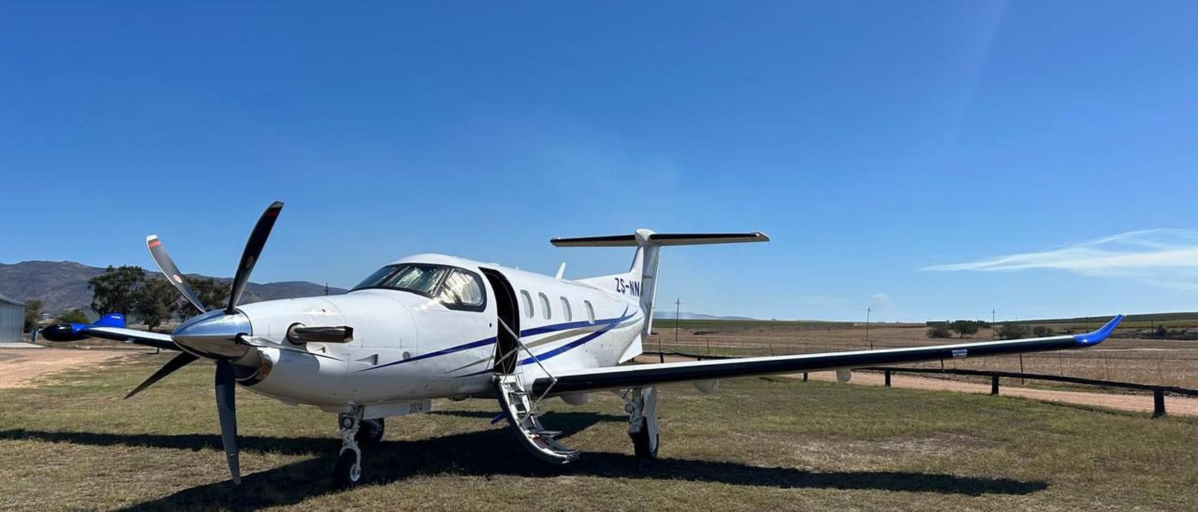 Pilatus PC-12 executive turboprop parked on a grass airstrip in the Western Cape before a corporate charter
